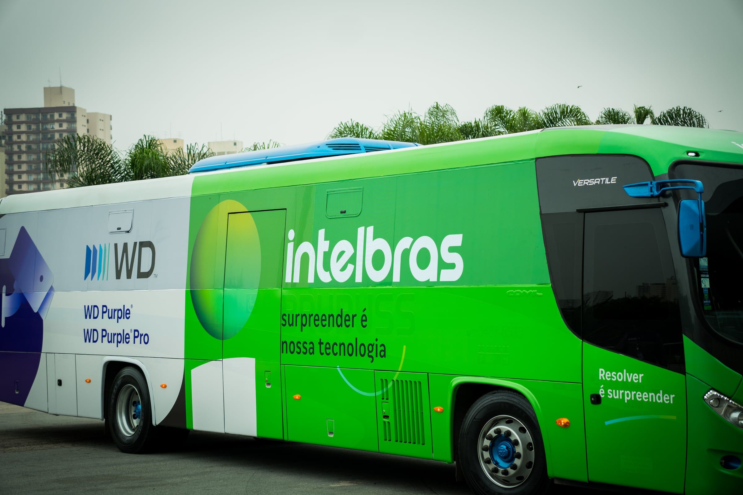 Ônibus da Intelbras e da WD adesivado de verde, estacionado na feira
