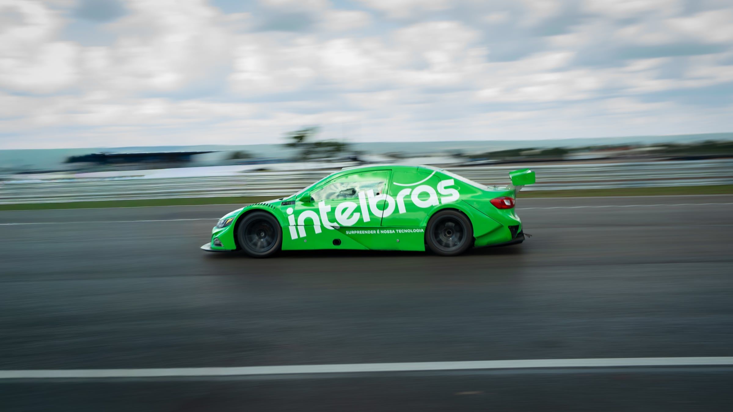 Carro verde da Intelbras em alta velocidade na pista, com o fundo borrado