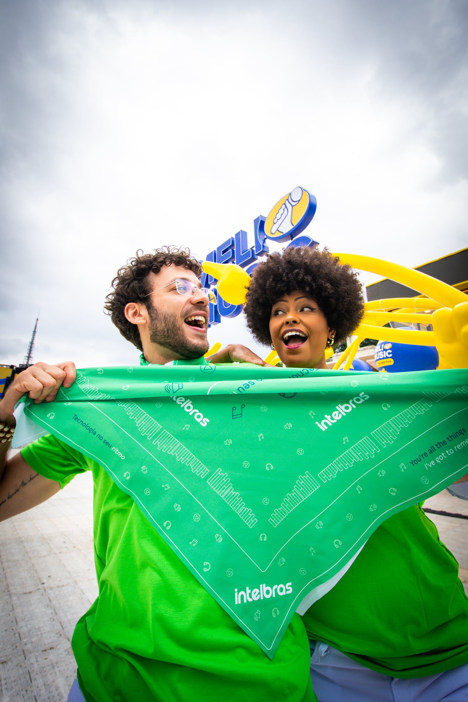 Dois fãs sorrindo e mostrando a bandana verde da Intelbras