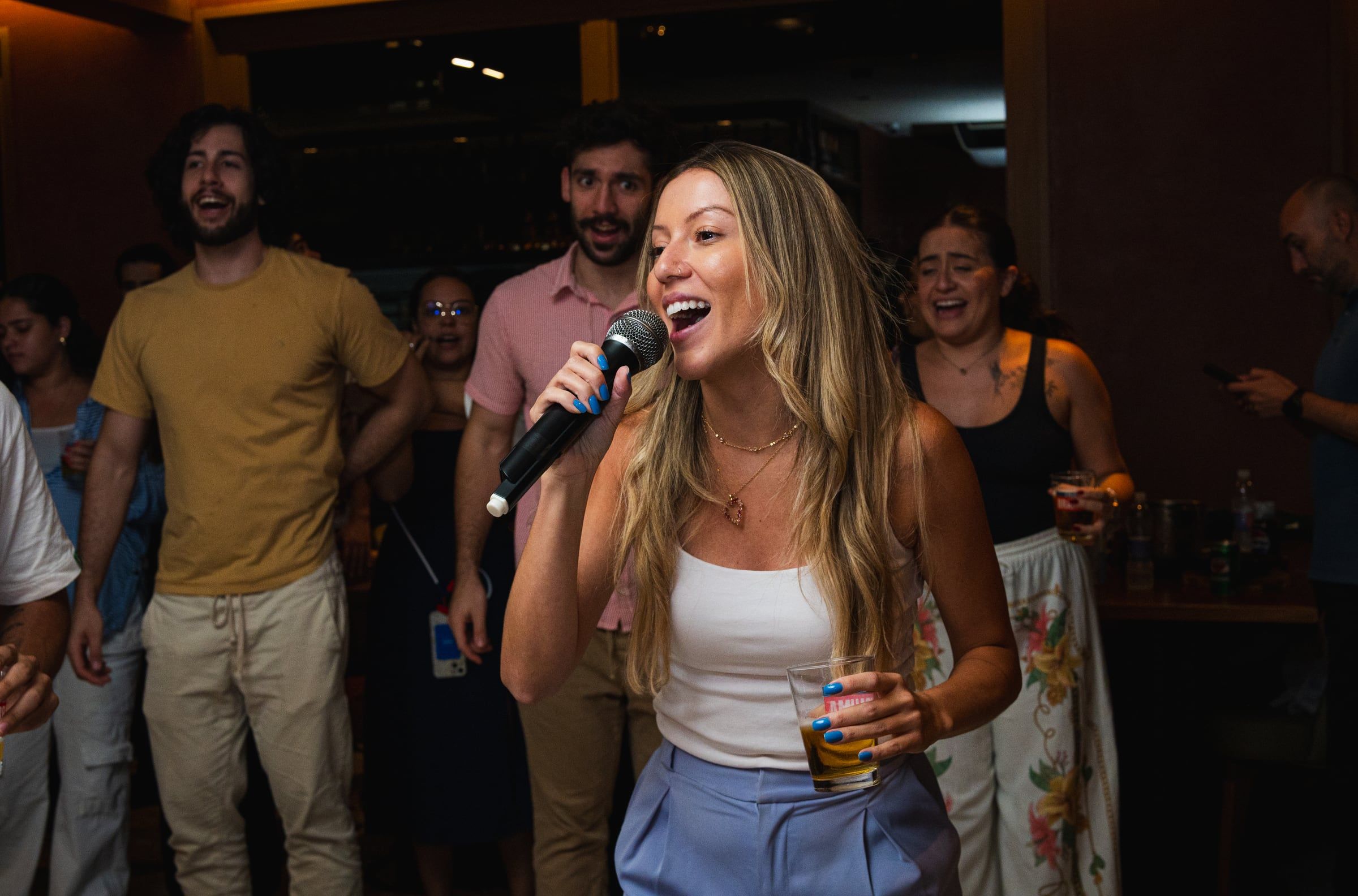 Mulher cantando no microfone no meio do bar lotado